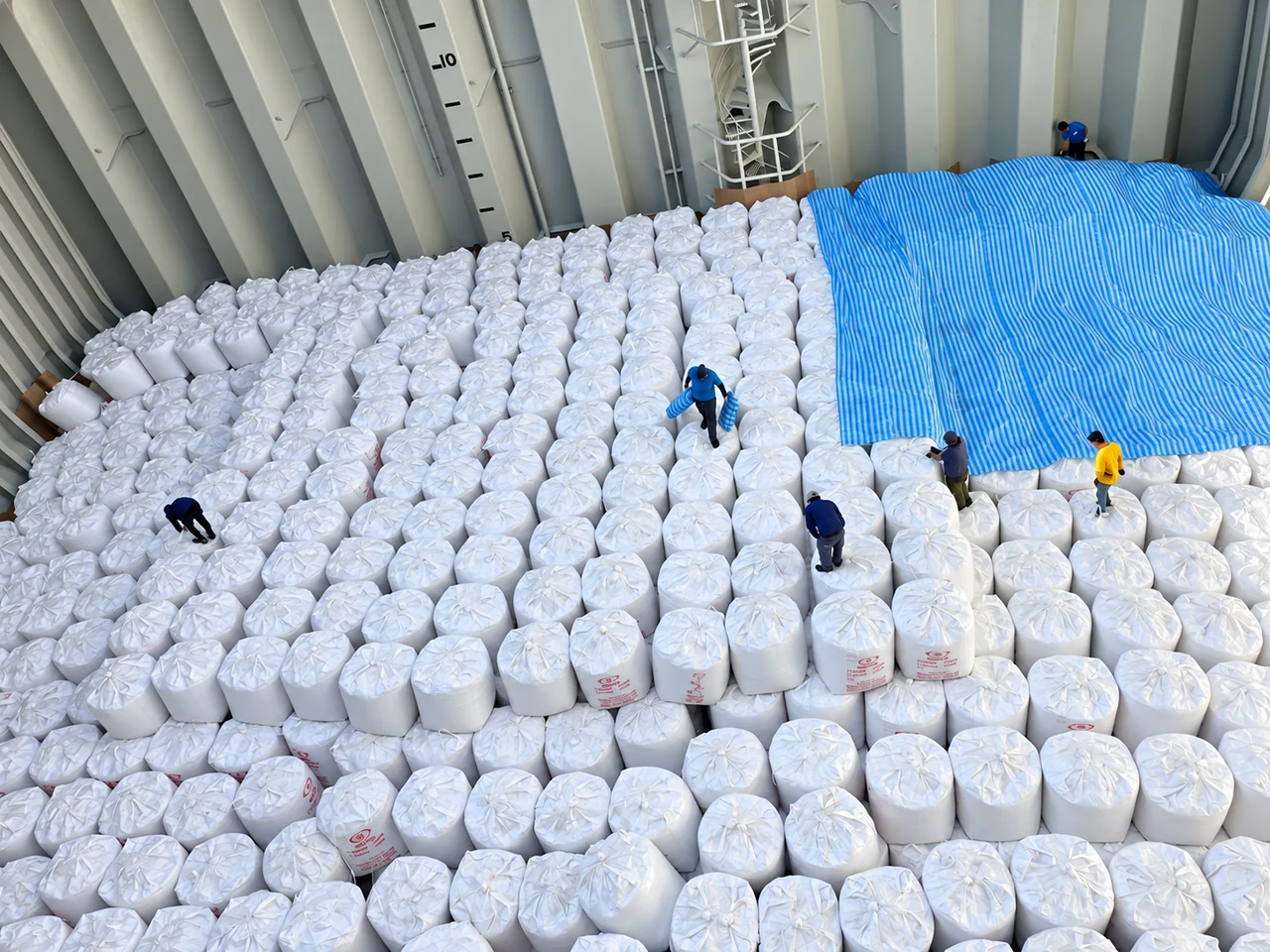 Rows of super sacks arranged in the hold, with sheeting covering part of the cargo.