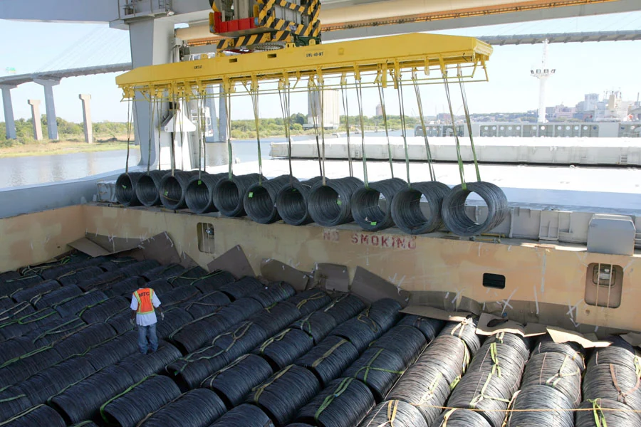 Wire rod coils being lowered into the hold using a lifting beam and slings.